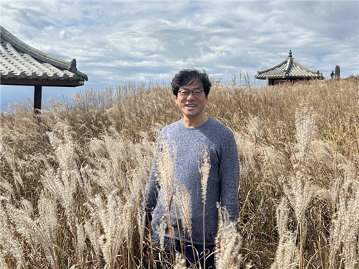 바람에 살랑거리며 흔들리는 갈대밭과 해맑게 웃고 있는 김성해 교수 (사진 본인 제공)